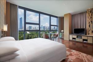 una camera da letto con un grande letto bianco e una grande finestra di The OCT Harbour, Shenzhen - Marriott Executive Apartments a Shenzhen