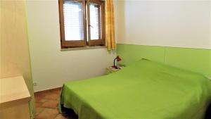 a green bedroom with a bed and a window at Taormina al mare Villetta in Mazzeo