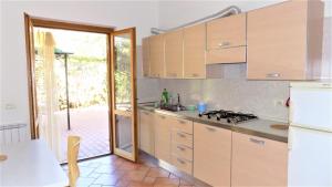 a kitchen with wooden cabinets and a door to a patio at Taormina al mare Villetta in Mazzeo
