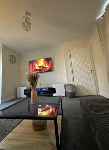 a living room with a table and a tv on the wall at The Hideaway by Elegant Apartments in Bradford