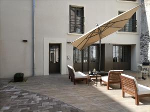patio z krzesłami, stołem i parasolem w obiekcie Villa Buffon w mieście Angers