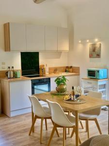 une cuisine avec une table et des chaises en bois ainsi qu'une cuisine avec des placards blancs dans l'établissement Appartement neuf et au calme proche Avignon, à Althen-des-Paluds