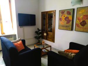 sala de estar con 2 sillas y TV de pantalla plana en Mameli Suite, en Spoleto