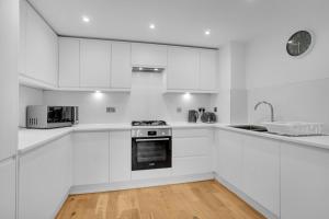 cocina blanca con electrodomésticos blancos y reloj en Kemptown Coastal By My Getaways, en Brighton & Hove