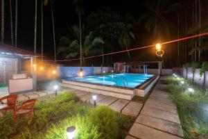 a swimming pool with lights in a backyard at night at Senses Havelock resort in Havelock Island