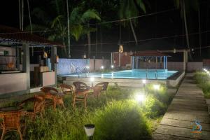 a patio with chairs and a swimming pool at night at Senses Havelock resort in Havelock Island