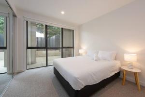 - une chambre avec un lit blanc et une grande fenêtre dans l'établissement 3BR Apt w/ Parking - 600m to Chadstone!, à Oakleigh
