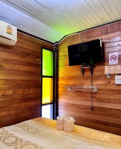 a room with a flat screen tv on a wooden wall at MrT Riverside Sampran มิสเตอร์ที โฮมสเตย์-ช้องนาง in Sam Phran