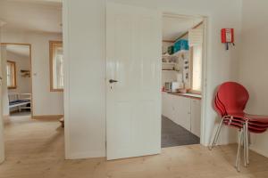 a kitchen with white walls and a red chair at Breathtaking View / 5-BR House / Scenic Village in Bøur