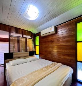 1 dormitorio con 2 camas, paredes y ventanas de madera en MrT Riverside Sampran มิสเตอร์ที โฮมสเตย์-ช้องนาง, en Sam Phran