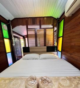 Una cama grande en una habitación con vidrieras. en MrT Riverside Sampran มิสเตอร์ที โฮมสเตย์-ช้องนาง, en Sam Phran