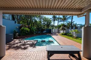 a swimming pool in a yard with a bench at Cozy, 2 bedroom beachfront apartment in Ballito