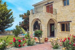 une maison en pierre avec un balcon et des fleurs dans l'établissement Villa Agathi, à Argaka