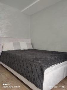 uma cama com um edredão preto num quarto em Посуточно! Современная смарт-квартира м. Дворец спорта, Олимпийская. em Kharkov