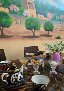 einen Tisch mit Platten und Schüsseln darauf mit einem Gemälde in der Unterkunft Khiva Khan Hotel in Xiva