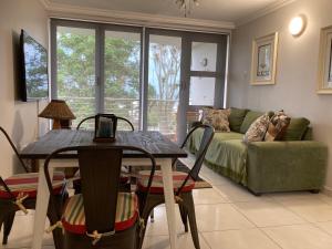 a living room with a table and a couch at Cozy, 2 bedroom beachfront apartment in Ballito