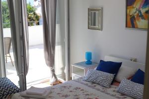 ein Schlafzimmer mit einem Bett mit blauen Kissen und einem Fenster in der Unterkunft App Sanny with nice terrace in Malinska