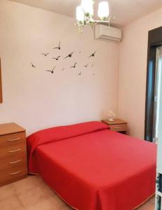 ein Schlafzimmer mit einem roten Bett mit Vögeln an der Wand in der Unterkunft Fresco relax appartamento Finale di Pollina in Finale