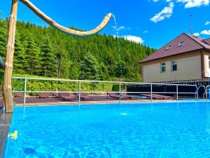 a large swimming pool with blue water in front of a house at Hotel U STUDÁNKY in Jablunkov