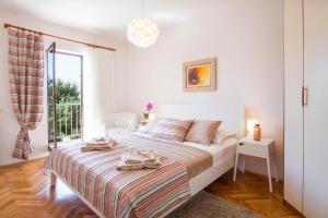 ein weißes Schlafzimmer mit einem Bett und einem Fenster in der Unterkunft App Sanny with nice terrace in Malinska