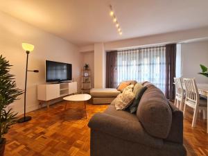 a living room with a couch and a table and a television at APARTAMENTO Delia in Gijón