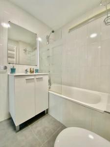 a white bathroom with a tub and a toilet and a sink at Charming Gran Vía V - Largas Estancias in Madrid