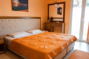 - une chambre avec un grand lit et une couverture orange dans l'établissement Antheia Apartments, à Agios Stefanos