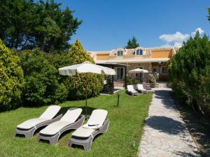 a group of lounge chairs and an umbrella in the grass at Peroulades Luxury Villa in Peroulades