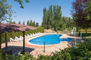 a swimming pool with chairs and an umbrella at Casa Rural Las Melias in Ciudad Real