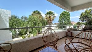 d'un balcon avec deux chaises et une vue sur les arbres. dans l'établissement Bouganville en Eureka, à Costa del Silencio
