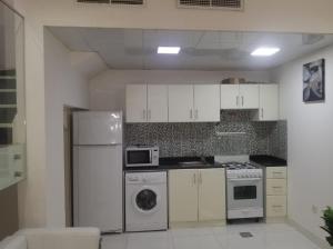 a kitchen with a white refrigerator and a microwave at Amazing One-Bedroom Villa TownHouse in Dubai
