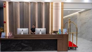 a person sitting at a desk with two laptops at Venus Royale Hotel in Coron