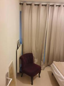 - une chambre avec une chaise et un rideau dans l'établissement Le Vallis Curans, à Saint-Raphaël