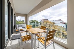 une salle à manger avec une table, des chaises et une grande fenêtre dans l'établissement Modern 2 bedroom apartment - Soleia 2 Apartment A9, à Pereybere