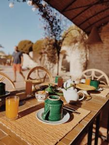 una mesa de madera con platos verdes y tazas. en Maison Belhazar en Essaouira
