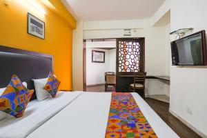 a bedroom with a bed and a tv on a wall at FabHotel All In One in New Delhi