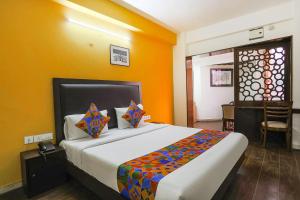 a bedroom with a large bed with an orange wall at FabHotel All In One in New Delhi