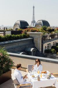 a man and woman sitting at a table with a laptop at Hotel The Peninsula Paris in Paris