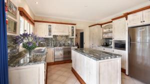 cocina con armarios blancos y encimeras de granito en The Manor in Blue Mountains, en Wentworth Falls