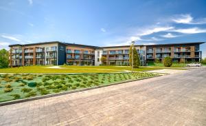 un grand bâtiment avec un jardin en face dans l'établissement Apartamenty Laguna Beskidów - A95, à Zarzecze