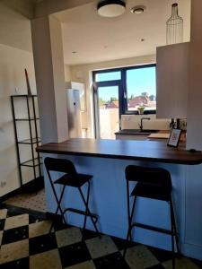 a kitchen with a counter and two bar stools at Appartement 2 chambres in Aire-sur-la-Lys