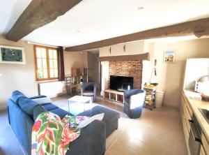 ein Wohnzimmer mit einem blauen Sofa und einem Kamin in der Unterkunft Maison Normande proche mer in Blosseville