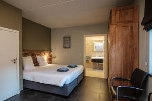 een slaapkamer met een bed en een badkamer met een wastafel bij Craywinckelhof Streekbelevingscentrum in Lubbeek