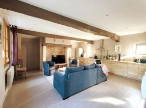 ein Wohnzimmer mit einem blauen Sofa und einer Küche in der Unterkunft Maison Normande proche mer in Blosseville