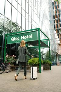 a woman pulling a suitcase in front of a hotel at Qbic Amsterdam WTC in Amsterdam