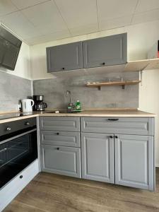 una cocina con armarios blancos y electrodomésticos negros en OF01 71m² große Unterkunft für bis zu 5 Personen, en Heusenstamm