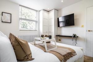 倫敦的住宿－Livestay-Luxury Kentish Town Apartments，卧室配有一张床,墙上配有电视。