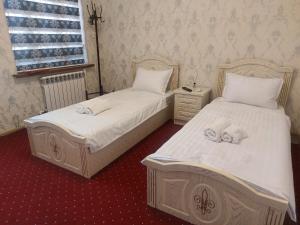 two beds in a room with white sheets and towels at Family guest house SEVEN in Samarkand
