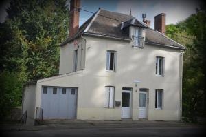 ein altes weißes Haus mit Garage in der Unterkunft Au bord de l'eau in Chambon-sur-Voueize