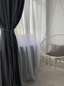 a swing in front of a window with curtains at Britannia ShortStay Apartment Caransebes in Caransebeş